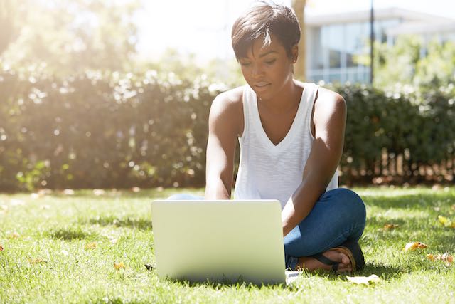 Young woman working outside on laptop computer.