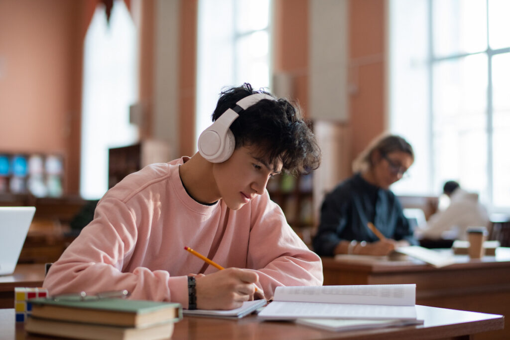 Young Asian man studying with pencil in a library.